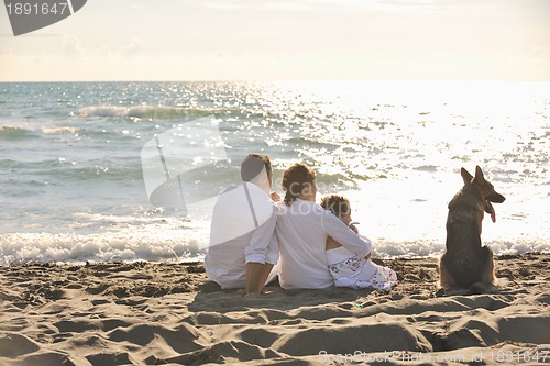 Image of happy family playing with dog on beach