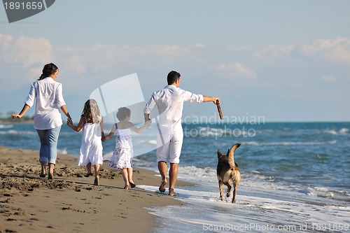 Image of happy family playing with dog on beach
