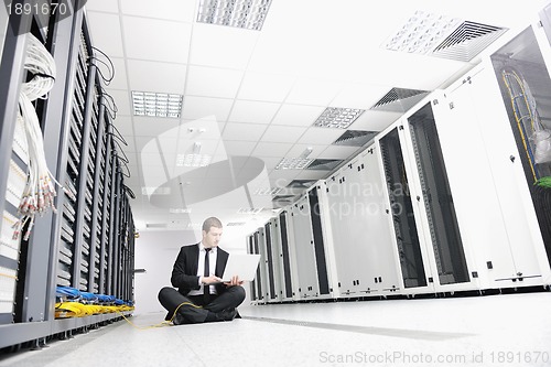 Image of businessman with laptop in network server room