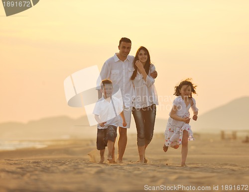 Image of happy young family have fun on beach at sunset