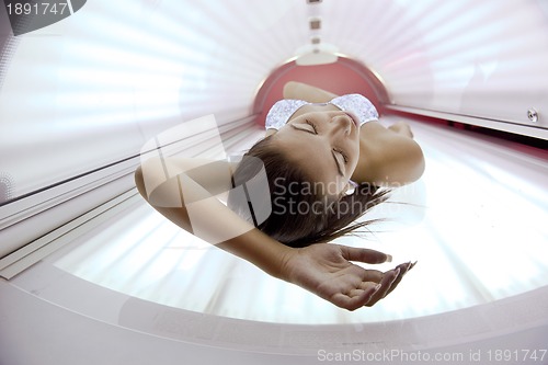 Image of Beautiful young woman tanning in solarium