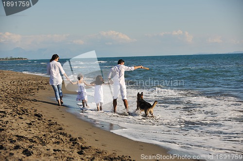 Image of happy family playing with dog on beach