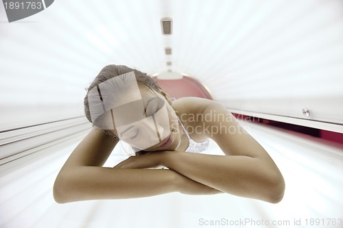 Image of Beautiful young woman tanning in solarium