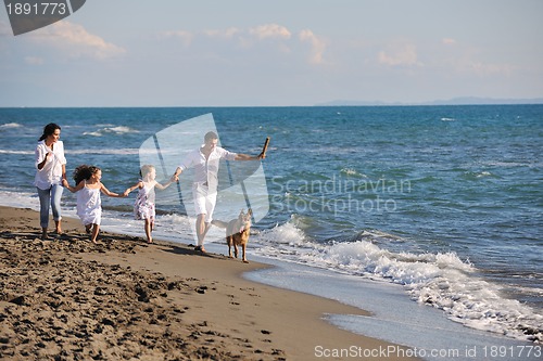 Image of happy family playing with dog on beach