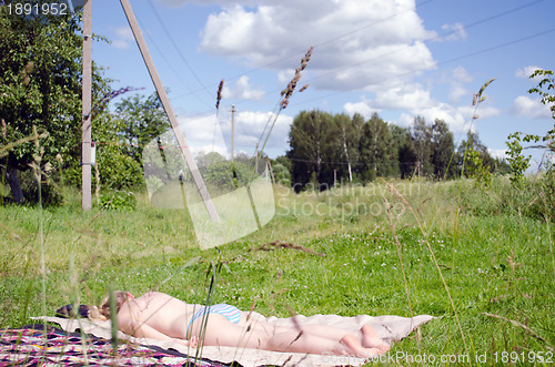 Image of Half nude woman  sunbathing plaid in rural meadow 