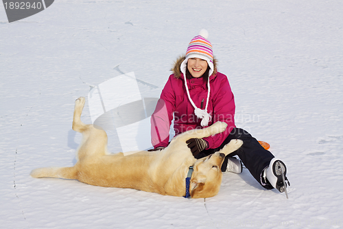 Image of Girl on ice skates playing with dog
