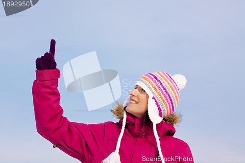 Image of Pretty girl in witer clothes pointing upwards