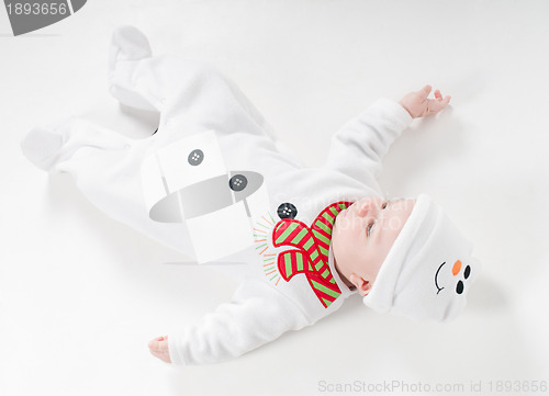 Image of Baby boy in snowman costume lying on the floor