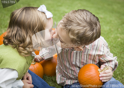 Image of Cute Young Brother and Sister Kiss At the Pumpkin Patch