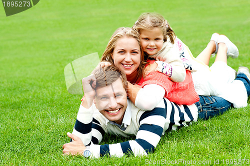 Image of Smiling family of three piled on top of each other