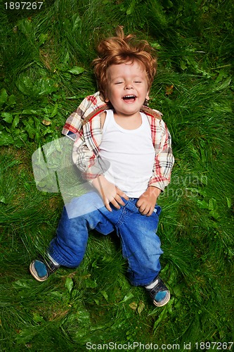 Image of adorable kid laughing on grass