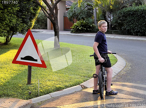 Image of Young Boy Stopped Bicycle at Speed Bump