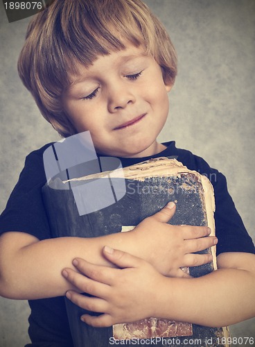 Image of Little boy hugging an old book