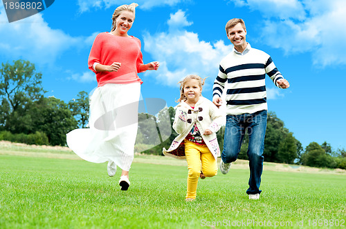 Image of Young couple racing with their cute little daughter