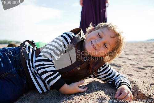 Image of Smiling boy lying on the beach.