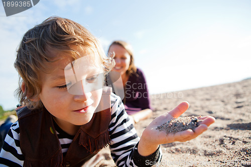 Image of Child with sand in hand at beach.