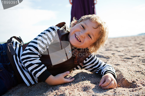 Image of Smiling boy lying on the beach.