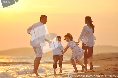 Image of happy young family have fun on beach at sunset