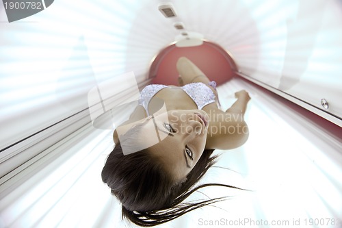 Image of Beautiful young woman tanning in solarium