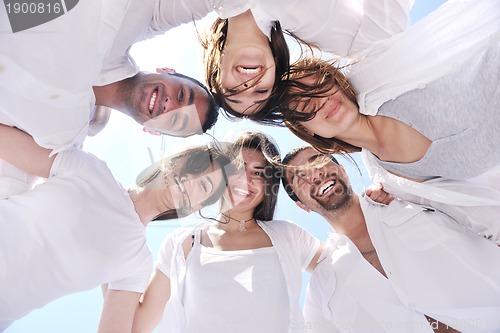 Image of Group of happy young people in circle at beach