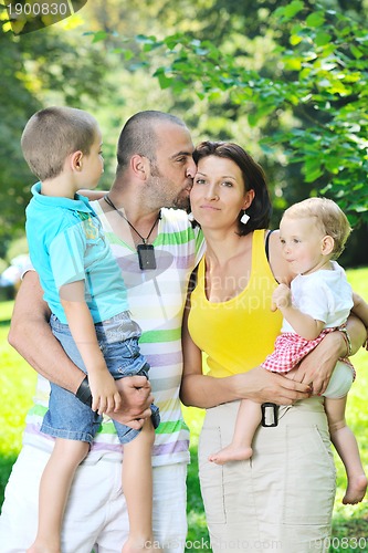 Image of happy young couple with their children have fun at park