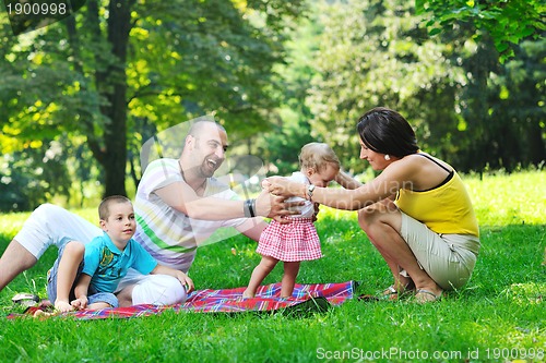 Image of happy young couple with their children have fun at park