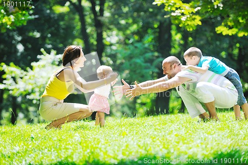 Image of happy young couple with their children have fun at park