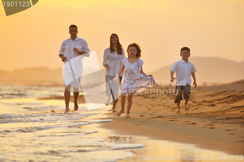 Image of happy young family have fun on beach at sunset
