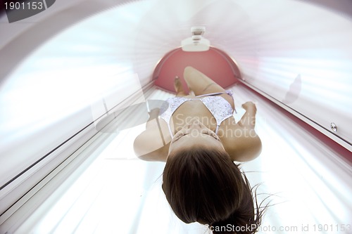 Image of Beautiful young woman tanning in solarium