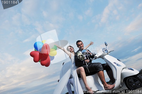 Image of just married couple on the beach ride white scooter