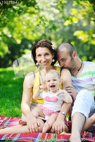 Image of happy young couple with their children have fun at park