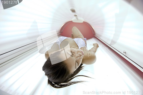 Image of Beautiful young woman tanning in solarium