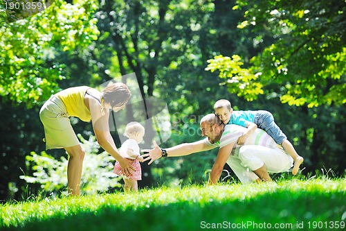 Image of happy young couple with their children have fun at park
