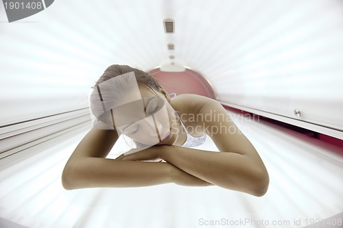 Image of Beautiful young woman tanning in solarium