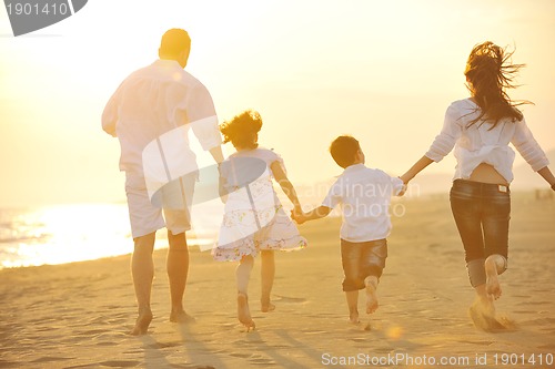 Image of happy young family have fun on beach at sunset