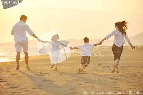 Image of happy young family have fun on beach at sunset