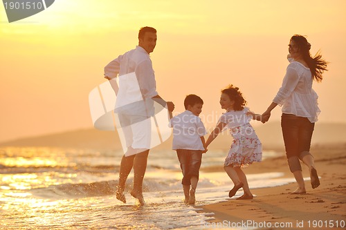 Image of happy young family have fun on beach at sunset
