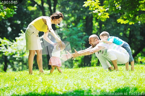 Image of happy young couple with their children have fun at park