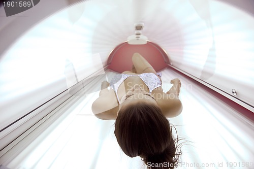 Image of Beautiful young woman tanning in solarium