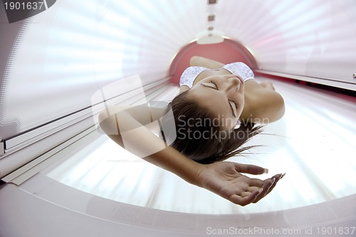 Image of Beautiful young woman tanning in solarium