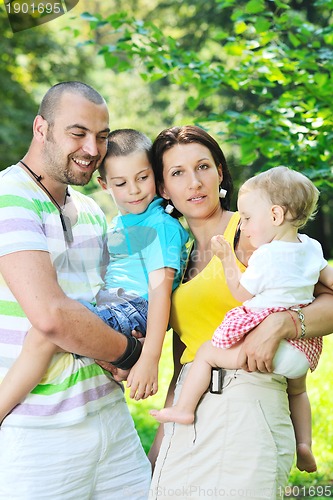 Image of happy young couple with their children have fun at park
