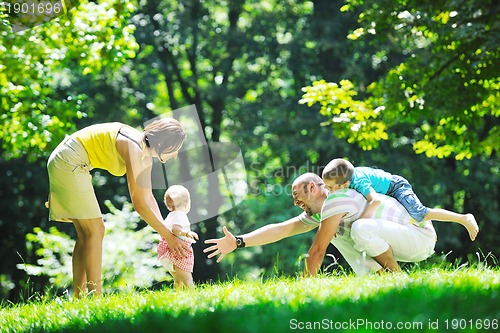Image of happy young couple with their children have fun at park