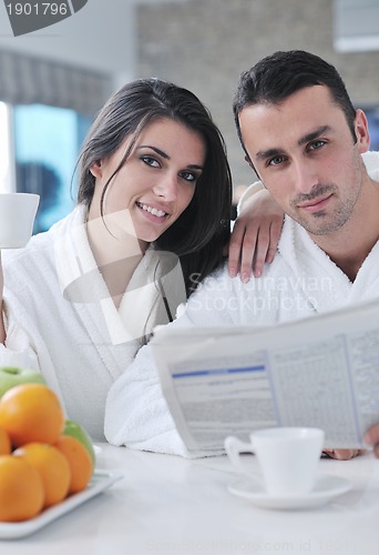 Image of Happy couple reading the newspaper in the kitchen at breakfast