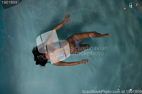 Image of pretty young lady  relaxing in the swimming pool