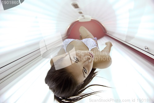 Image of Beautiful young woman tanning in solarium