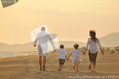 Image of happy young family have fun on beach at sunset