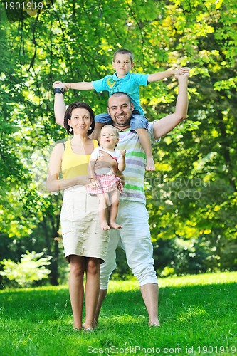 Image of happy young couple with their children have fun at park