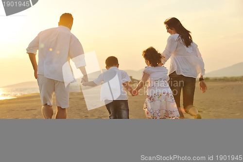 Image of happy young family have fun on beach at sunset