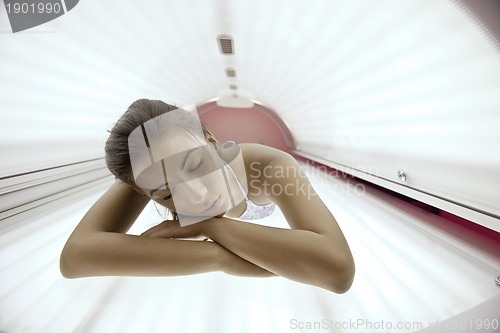 Image of Beautiful young woman tanning in solarium