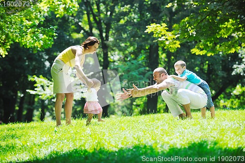 Image of happy young couple with their children have fun at park